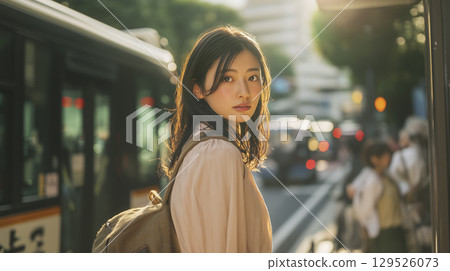 A woman waiting for a bus at a bus stop 129526073