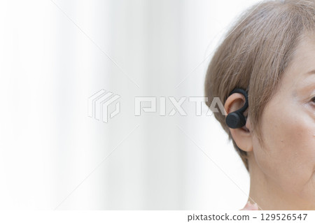 Senior woman wearing a hearing aid Senior woman wearing a hearing aid 129526547