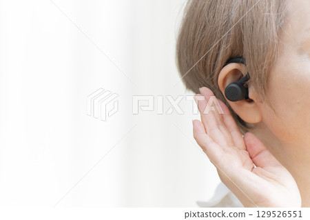 Senior woman wearing a hearing aid 129526551