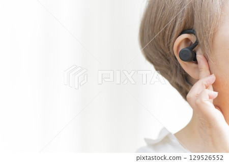 Senior woman wearing a hearing aid 129526552