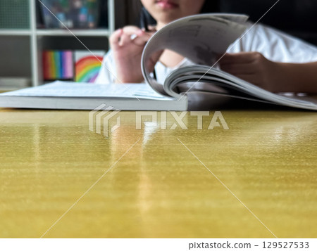 A student engages in independent learning, carefully completing workbook tasks without any assistance. A student engages in independent learning, carefully completing workbook tasks without any assistance. 129527533