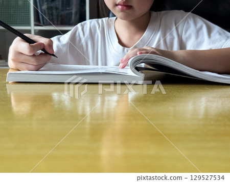 A student engages in independent learning, carefully completing workbook tasks without any assistance. 129527534