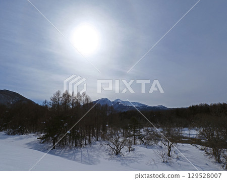 白雪皚皚的森林和白雪皚皚的磐梯山。天空中閃耀的太陽周圍,環繞著彩虹色的光環,美麗奪目。 白雪皚皚的森林和白雪皚皚的磐梯山。天空中閃耀的太陽周圍,環繞著彩虹色的光環,美麗奪目。 129528007