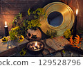 Mystic still life with skull, mirror, decorated magic book of spells, tansy flowers, black candles and witchy ritual objects on old table. Occult, esoteric, gothic and wicca concept Mystic still life with skull, mirror, decorated magic book of spells, tansy flowers, black candles and witchy ritual objects on old table. Occult, esoteric, gothic and wicca concept 129528796