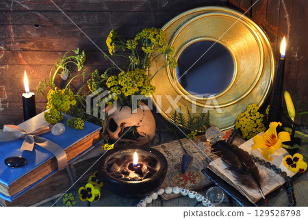 Mystic still life with magic books, tansy flowers, black candles and witchy ritual objects on old table. Occult, esoteric, gothic and wicca concept 129528798