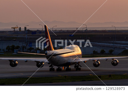 一架大型客機在夕陽下閃耀著橙色光芒 129528973