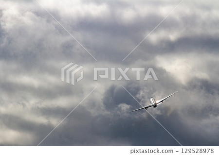 Airplane silhouette rising above cloudy skies 129528978