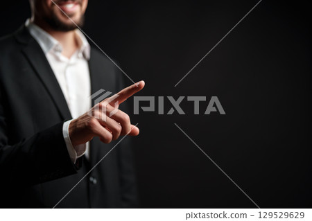 Businessman gesturing positively during a corporate presentation in a dark studio setting Businessman gesturing positively during a corporate presentation in a dark studio setting 129529629