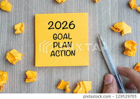 2026 Goal, Plan, Action word on yellow note with Businessman holding pen and crumbled paper on wooden table background. New Year New Start, Resolutions, Strategy concept 2026 Goal, Plan, Action word on yellow note with Businessman holding pen and crumbled paper on wooden table background. New Year New Start, Resolutions, Strategy concept 129529705