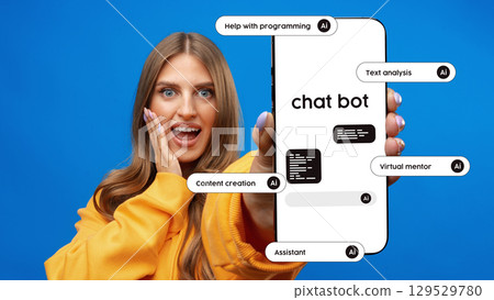 Excited user showcasing chatbot capabilities with smartphone against bright blue background 129529780