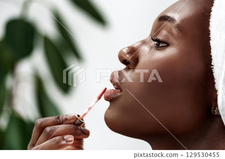 Woman applying lip gloss during a beauty routine in a bright, modern setting Woman applying lip gloss during a beauty routine in a bright, modern setting 129530455