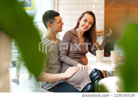 Couple sharing a joyful moment in a cozy cafe during the afternoon with warm drinks on the table 129530539