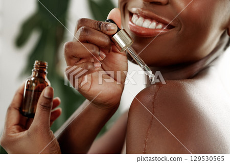 Skincare routine featuring serum application on shoulder in bright indoor setting 129530565