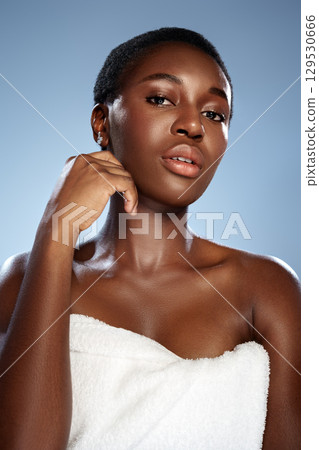 Young woman with short hair poses confidently against a blue background, showcasing natural beauty in a towel 129530666
