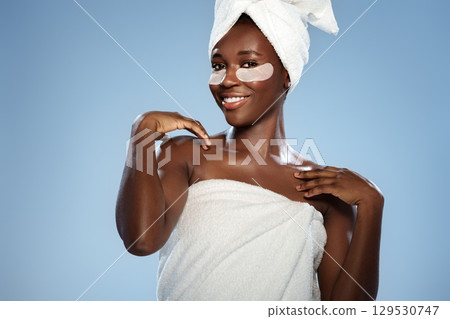 Woman applying skincare while smiling in a spa-like setting during daylight with a blue background Woman applying skincare while smiling in a spa-like setting during daylight with a blue background 129530747