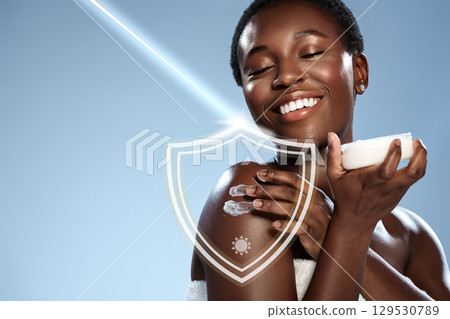 Smiling woman applies cream on her shoulder against a clear blue background during a skincare routine Smiling woman applies cream on her shoulder against a clear blue background during a skincare routine 129530789