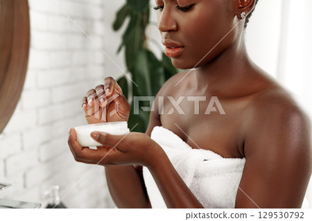 Woman applying moisturizer in a bathroom after a refreshing shower, focusing on skincare routine in natural light Woman applying moisturizer in a bathroom after a refreshing shower, focusing on skincare routine in natural light 129530792