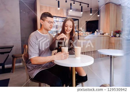 Couple enjoys coffee and conversation at modern cafe during cozy afternoon 129530942