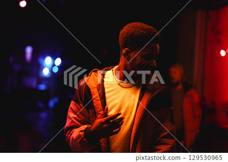 Vibrant night scene with a man enjoying music at a live event in a contrasting lit venue 129530965