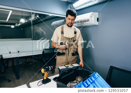 Skilled technician conducts maintenance in modern office space during daytime 129531057