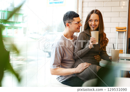 Couple enjoys drinks together in a cozy cafe during a sunny afternoon 129531090