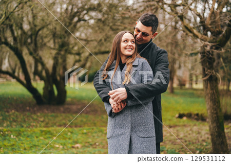 Couple enjoying a playful moment in a serene park during early spring 129531112