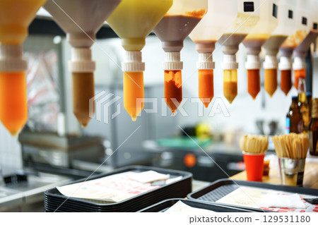 Squeezable condiments hanging in a food service area during a busy mealtime at a casual dining restaurant Squeezable condiments hanging in a food service area during a busy mealtime at a casual dining restaurant 129531180