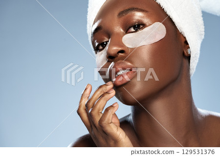 Woman applying skincare with eye patches in a relaxed home spa setting Woman applying skincare with eye patches in a relaxed home spa setting 129531376