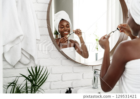 Woman applying skincare in modern bathroom with a warm and inviting atmosphere at morning time Woman applying skincare in modern bathroom with a warm and inviting atmosphere at morning time 129531421