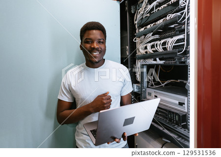 Technician working on network cables in a data center with laptop during daytime Technician working on network cables in a data center with laptop during daytime 129531536