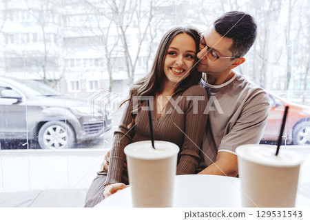 Couple enjoying a cozy moment at a cafe while sipping beverages on a winter day Couple enjoying a cozy moment at a cafe while sipping beverages on a winter day 129531543
