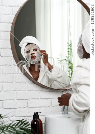 Enjoying a relaxing skincare routine with a facial mask in a bright bathroom Enjoying a relaxing skincare routine with a facial mask in a bright bathroom 129531608