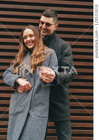 Couple enjoying a joyful moment together in urban setting with wooden background during a warm afternoon Couple enjoying a joyful moment together in urban setting with wooden background during a warm afternoon 129531618