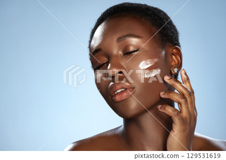 Model applying skincare product during a beauty routine in a studio with natural light, capturing the essence of self-care and wellness 129531619