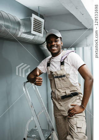 Skilled worker proudly completing installation in a modern building during daylight hours 129531698