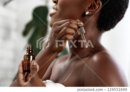 Woman applying skincare serum in a bright, modern bathroom during a self-care routine Woman applying skincare serum in a bright, modern bathroom during a self-care routine 129531699