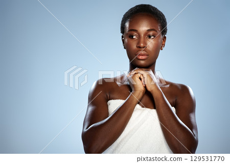 Model poses thoughtfully while wrapped in towel against a light blue background during a studio photoshoot capturing beauty and grace Model poses thoughtfully while wrapped in towel against a light blue background during a studio photoshoot capturing beauty and grace 129531770