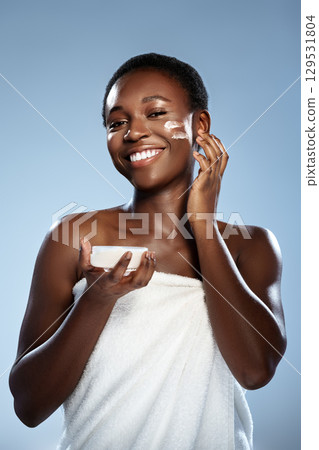 Woman applying skincare product with a joyful expression in a bright setting Woman applying skincare product with a joyful expression in a bright setting 129531804