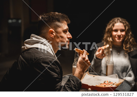 Friends enjoy late-night snacks at a cozy outdoor cafe in an urban setting while sharing laughter and stories 129531827
