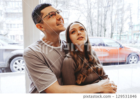 Couple enjoying each other's company in a cozy cafe during a rainy day while gazing out the window 129531846