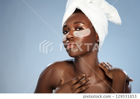 Woman with a towel on her head applying face mask in a calm indoor setting during a self-care routine 129531853