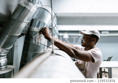 Technician working on ventilation system in modern office during daytime Technician working on ventilation system in modern office during daytime 129531858