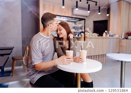 Young couple enjoys intimate moment with coffee in cozy cafe during afternoon 129531864