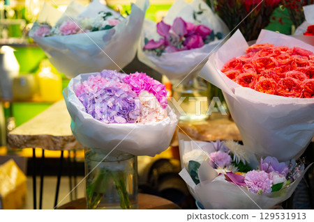 Colorful flower bouquets displayed in a vibrant shop during the daytime with bright lighting Colorful flower bouquets displayed in a vibrant shop during the daytime with bright lighting 129531913