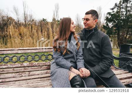 Couple enjoying a quiet moment on a park bench during a chilly afternoon in late fall Couple enjoying a quiet moment on a park bench during a chilly afternoon in late fall 129531918