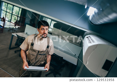 Worker installing lighting fixture in modern office space during daylight Worker installing lighting fixture in modern office space during daylight 129531958