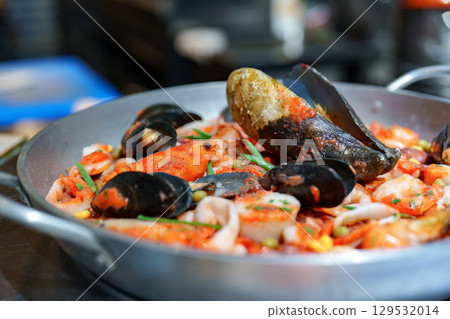 Fresh seafood paella with shrimp, mussels, and squid served in a traditional pan at a coastal restaurant during dinner time Fresh seafood paella with shrimp, mussels, and squid served in a traditional pan at a coastal restaurant during dinner time 129532014
