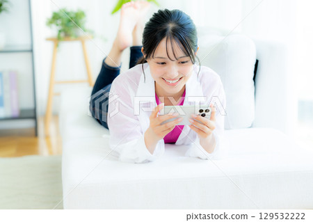 A young woman operating a smartphone in a room A young woman operating a smartphone in a room 129532222