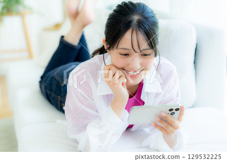 A young woman operating a smartphone in a room A young woman operating a smartphone in a room 129532225