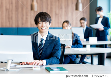 工作在辦公室的一個年輕商人 工作在辦公室的一個年輕商人 129532469